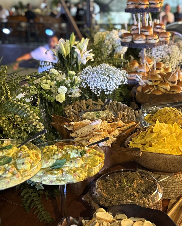Buffet de coquetel com saladas, tábuas, sliders e flores