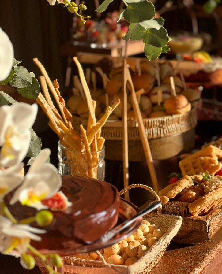 Mesa rústica do Vírgula com bolo de chocolate, pão de queijo e palitos