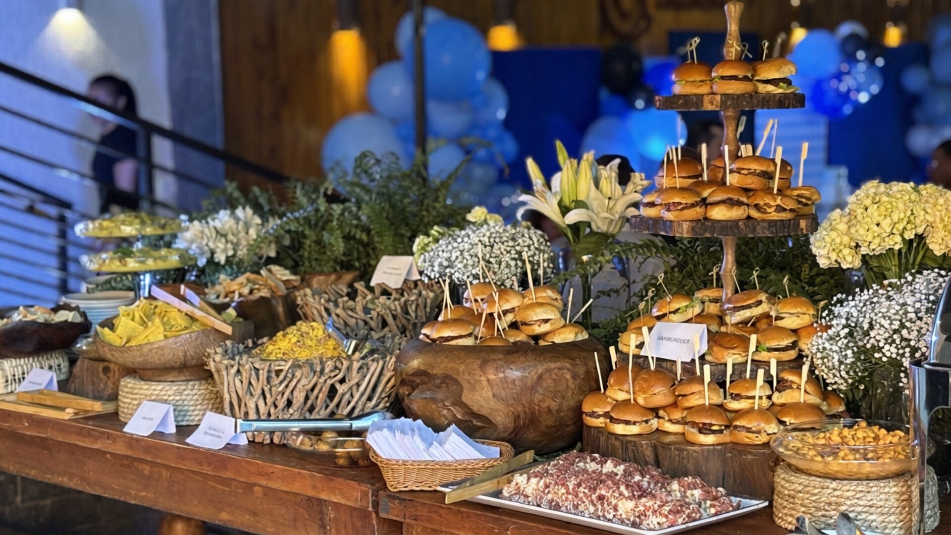 Mesa de buffet do Vírgula com mini hambúrgueres, flores e decoração para evento